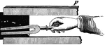 A hand holding a U-shaped tuning fork.