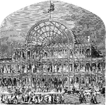 Men and women are standing outside the entrance to the Crystal Palace. Horses and carriages are also outside. At the top of the building is a flag, and there are more flags along the top of either side of the building.