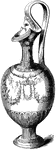 This jug has a handle which is sculpted higher than the jug itself. A woman's face is seen near the jug's opening. Floral patterns decorate the outer portion of the jug. The base is smaller than the main portion.