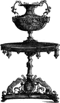 This table and vase are an Italian design. The vase stands on a pedestal and has a wide short body, while its handles are designed in a scrolling effect. The table is richly decorated with figures at the base.