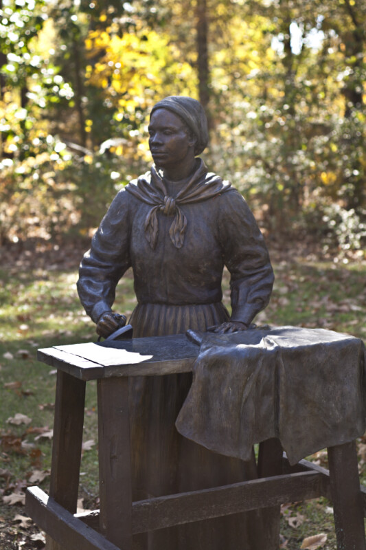 A Bronze Sculpture of a Woman Doing Laundry