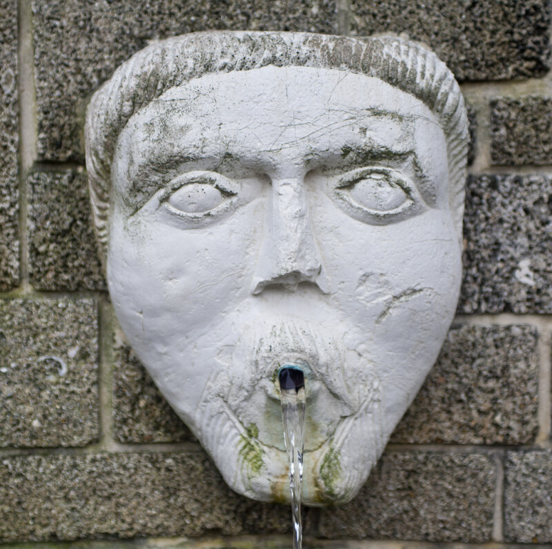 A Sculpted Face, with a Beard and Mustache, on a Masonry Wall