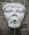 A Sculpted Face, with Curly Hair, on a Masonry Wall