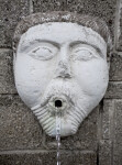 A Sculpted Face, with Round Cheeks, on a Masonry Wall