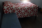 A Small Bed with a Red and White Quilt