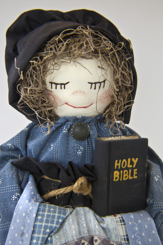Alabama Female Doll with Embroidered Face and Bonnet Holding the Holy Bible (Close Up)