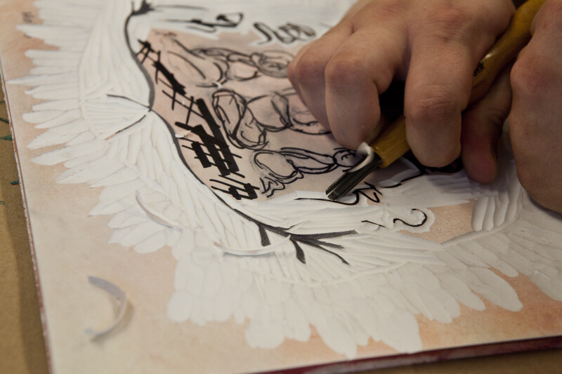 An artist carving into a sintra plate.