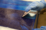An artist scraping excess ink off of an etching plate.