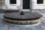 Black Cannonballs Stacked on a Wooden Covering of a Well