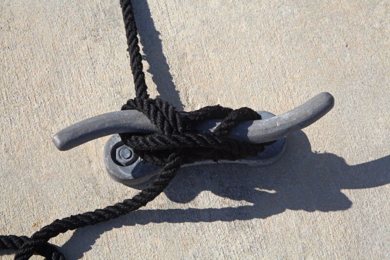 Black Rope Tied to a Wavy Dock Cleat