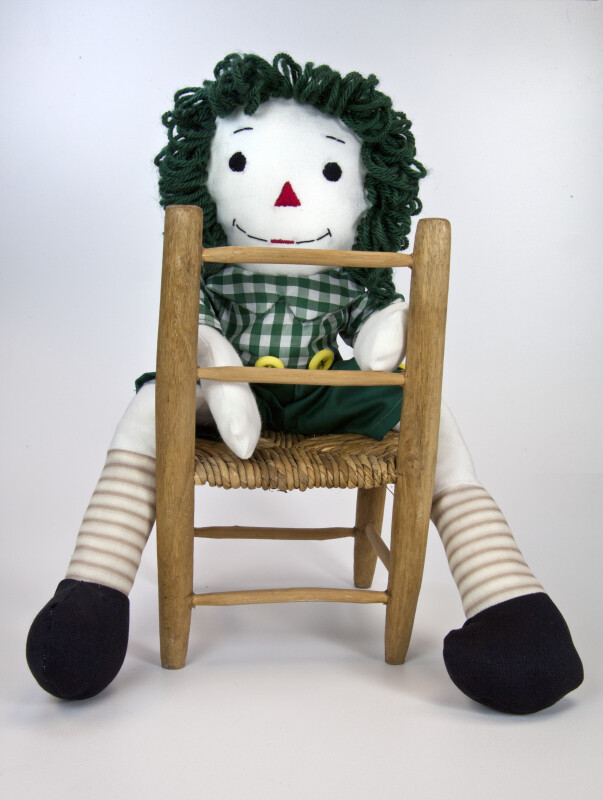 Indiana Raggedy Andy Doll with Yarn Hair Seated Backwards on a Wicker Chair (Full View)