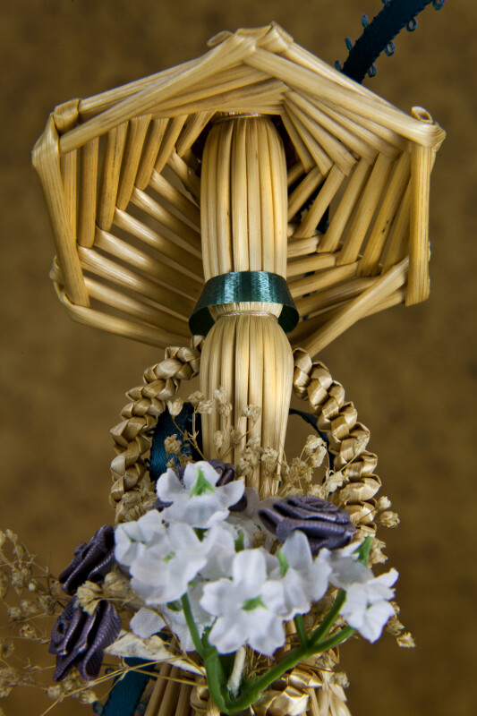 Manitoba, Canada - Faceless Female Figurine Made from Wheat Holding Bouquet of Artificial Flowers (Close Up)