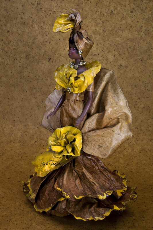 Martinique Female Plastic Doll with Clothing Made with Banana Leaves That Is Highlighted with Gold Paint (Three Quarter View)
