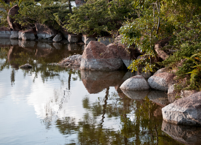 Reflective Pond with Reddish-Grey Rocks