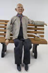Texas Elderly Male Daddy Long Legs Doll Sitting on a Bench with a Newspaper (Full View)