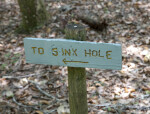 Wooden Sign Pointing in Direction of Sink Hole